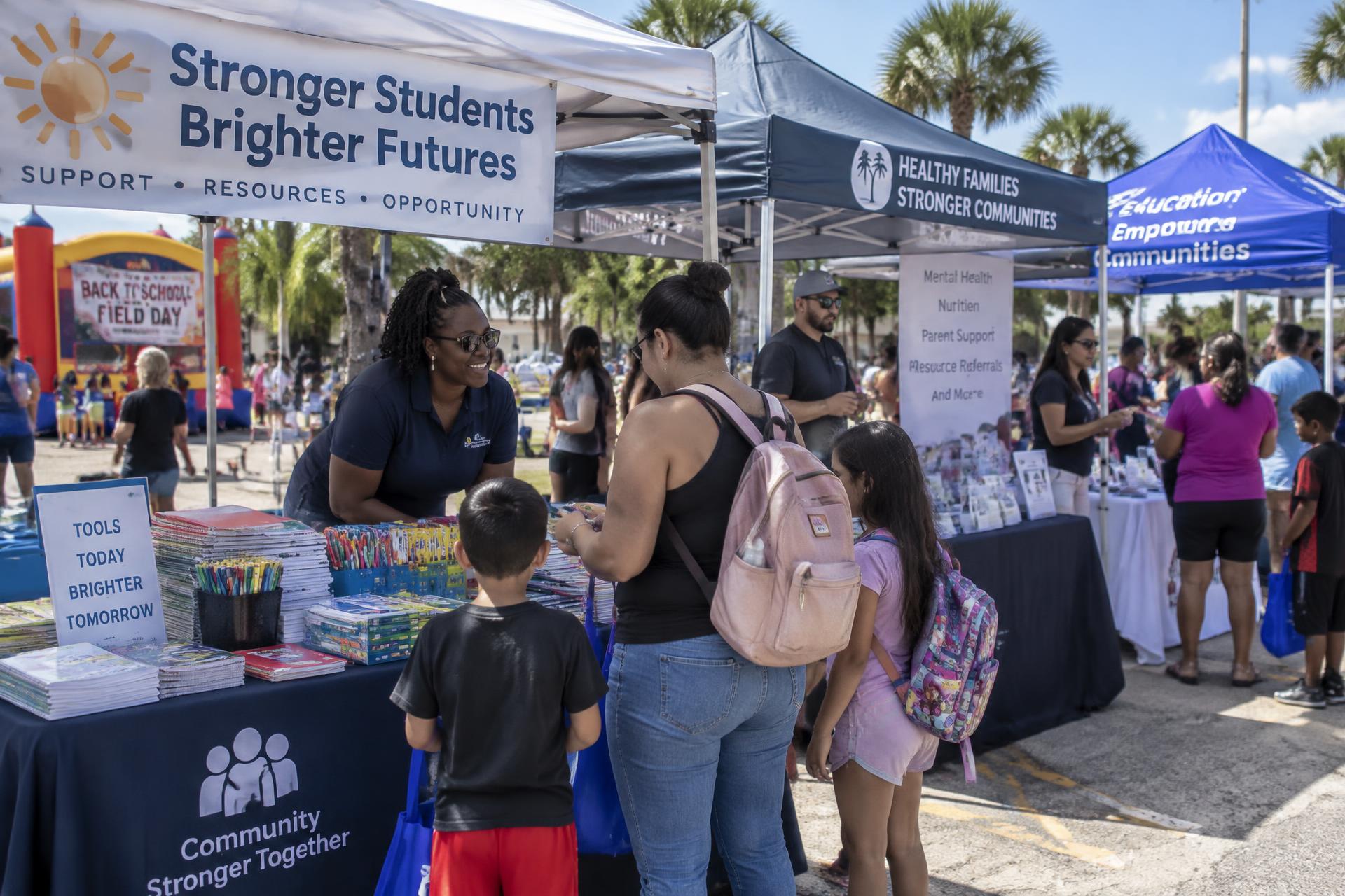 Families visiting vendor booths with school supplies and community resources